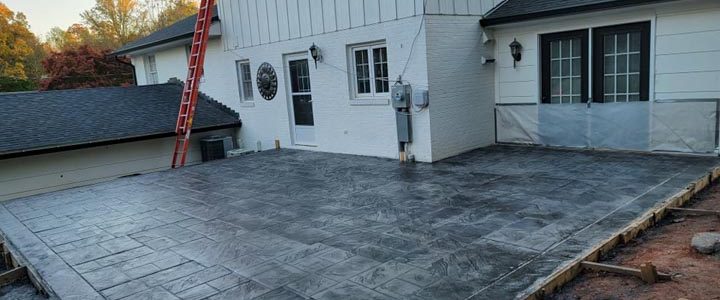 paver patio construction using concrete materials, a ladder leaning on the house exterior wall