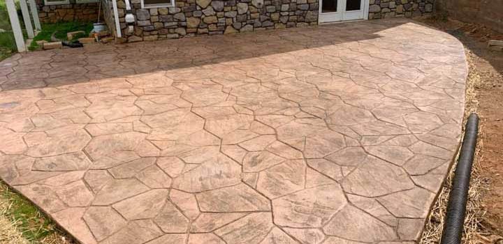 concrete stamped patio of a house with exterior wall made of stone veneers